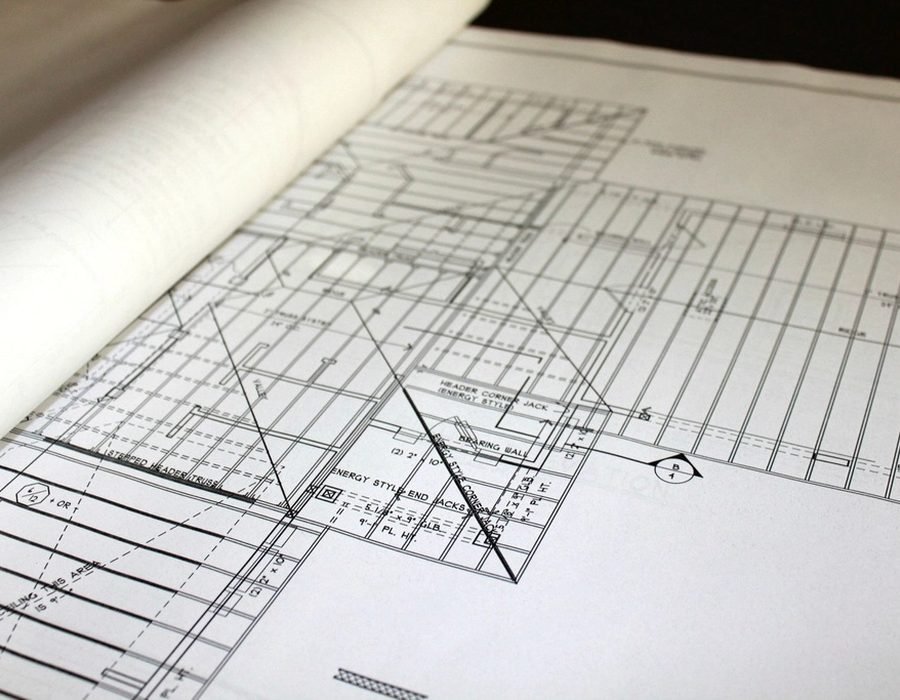 Planos arquitectónicos desplegados sobre una mesa junto a una escuadra