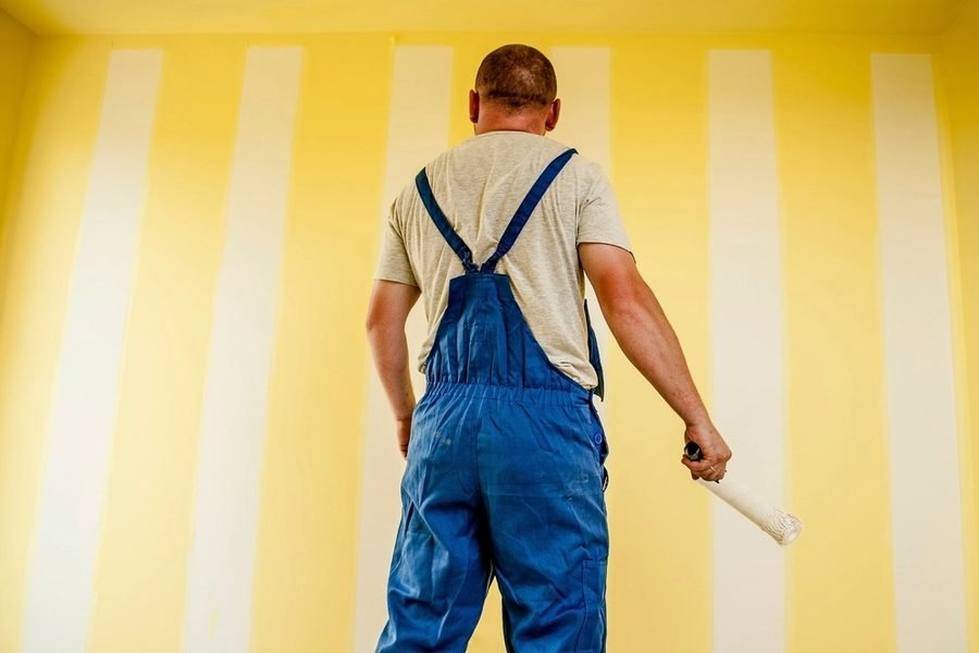 Trabajador aplicando pintura con rodillo sobre un muro interior
