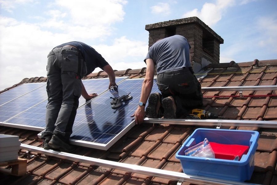 Dos técnicos instalando paneles solares sobre el tejado de una vivienda