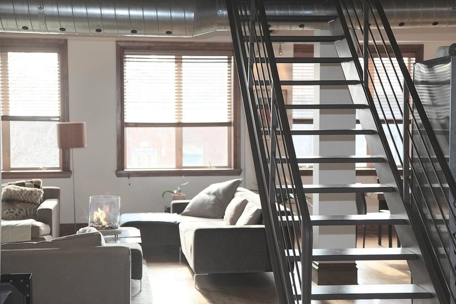 Sala remodelada con escalera metálica, ventanales y acabados nuevos